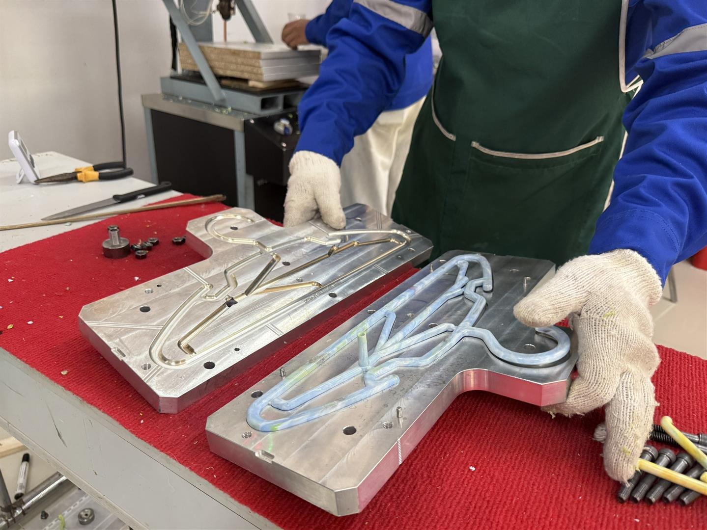 Staff producing hangers from recycled plastic bottle caps using molding equipment