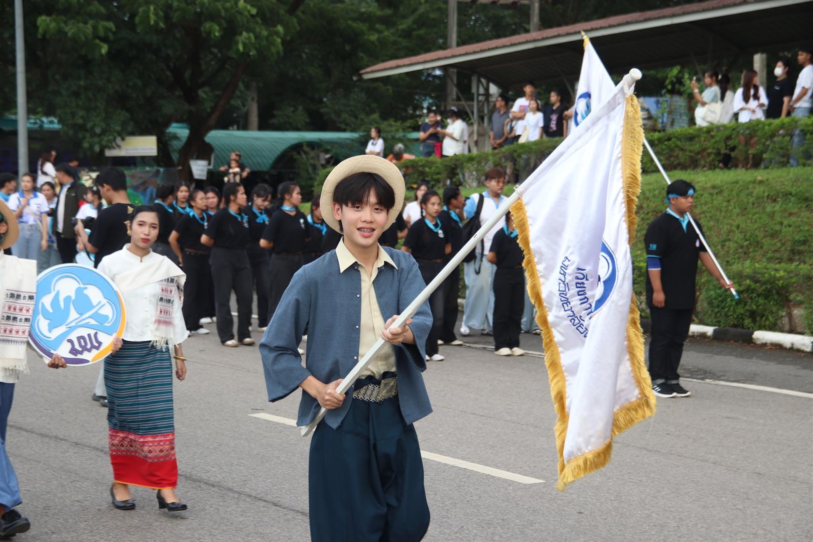 Students in traditional dress carrying decorative offerings during the walking into university activity 2025