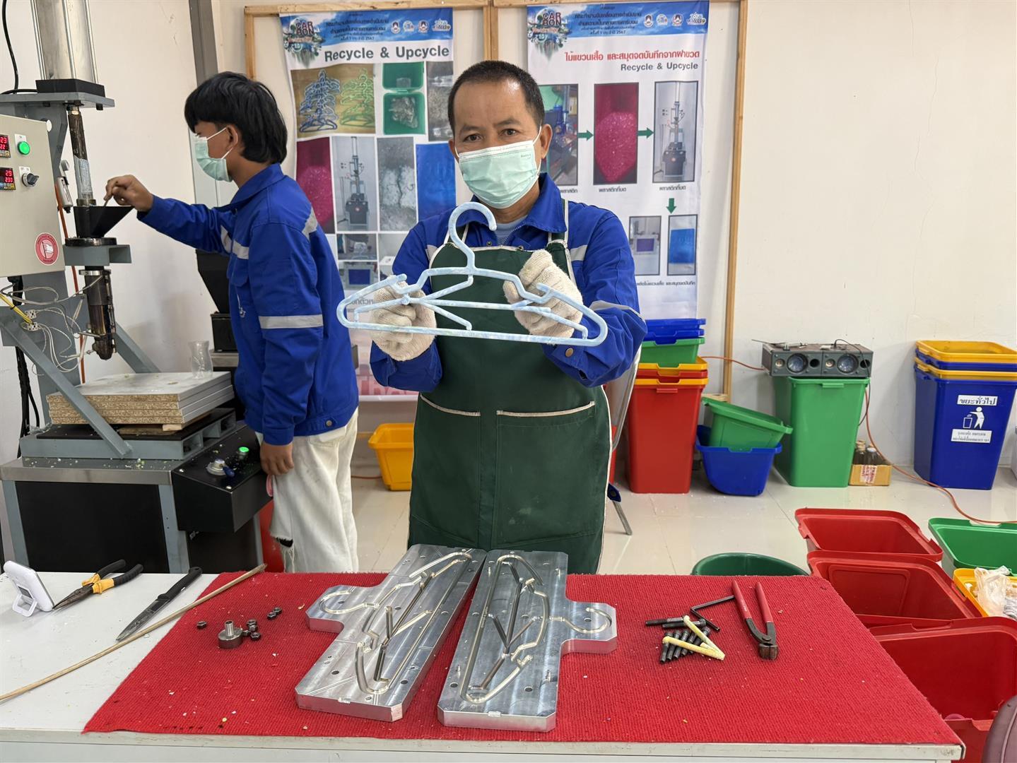 Staff producing hangers from recycled plastic bottle caps using molding equipment