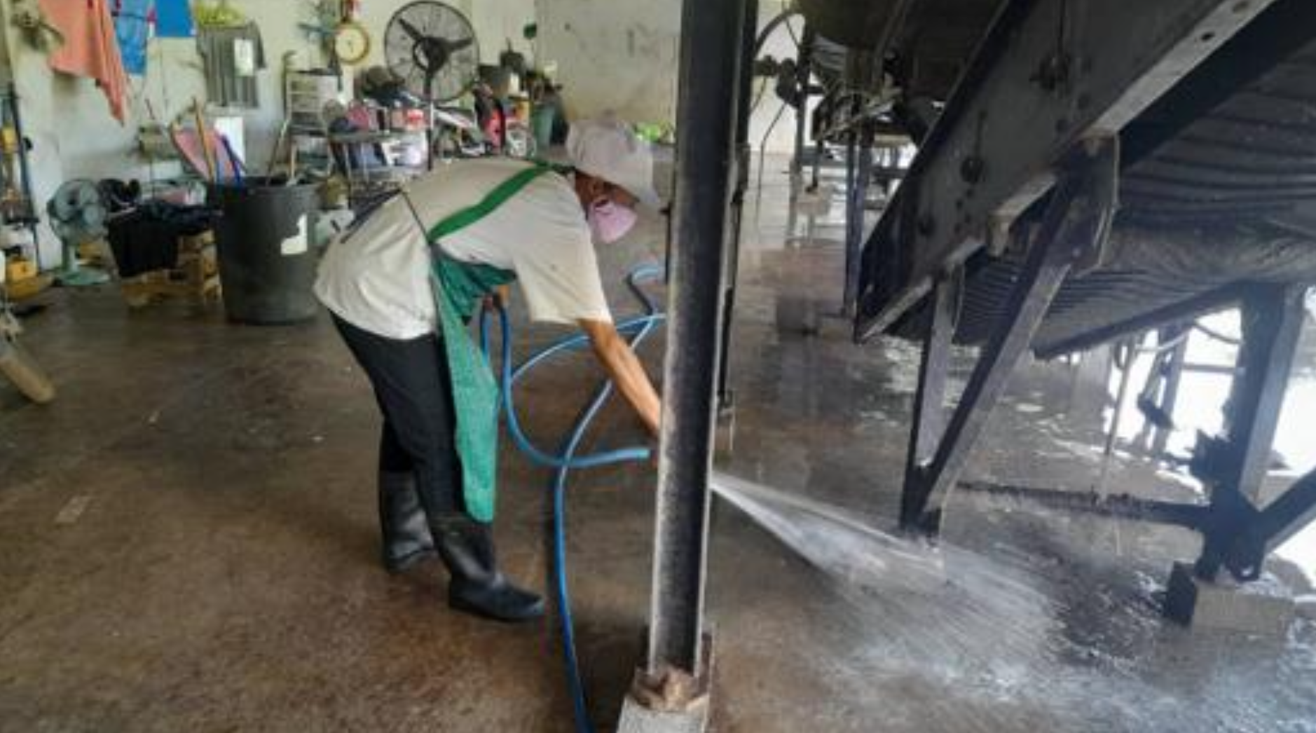Staff member washing the floor of the waste management building with treated water