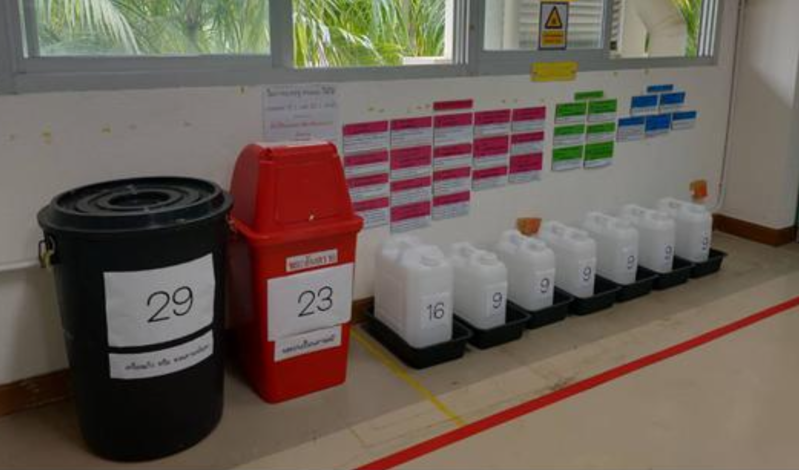 Hazardous waste containers labeled by code at the collection area