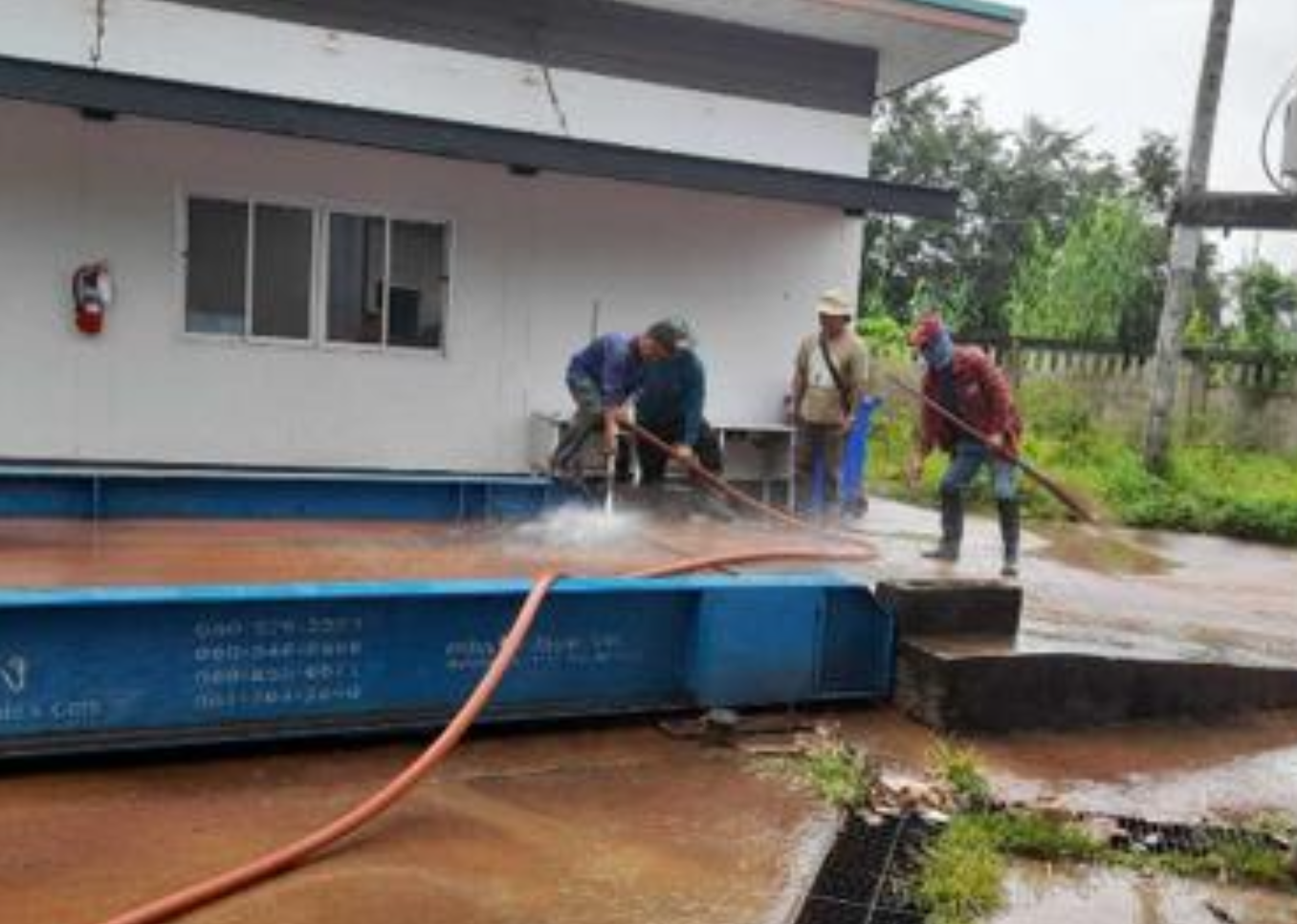 Staff member washing the floor outside the waste management building with treated water