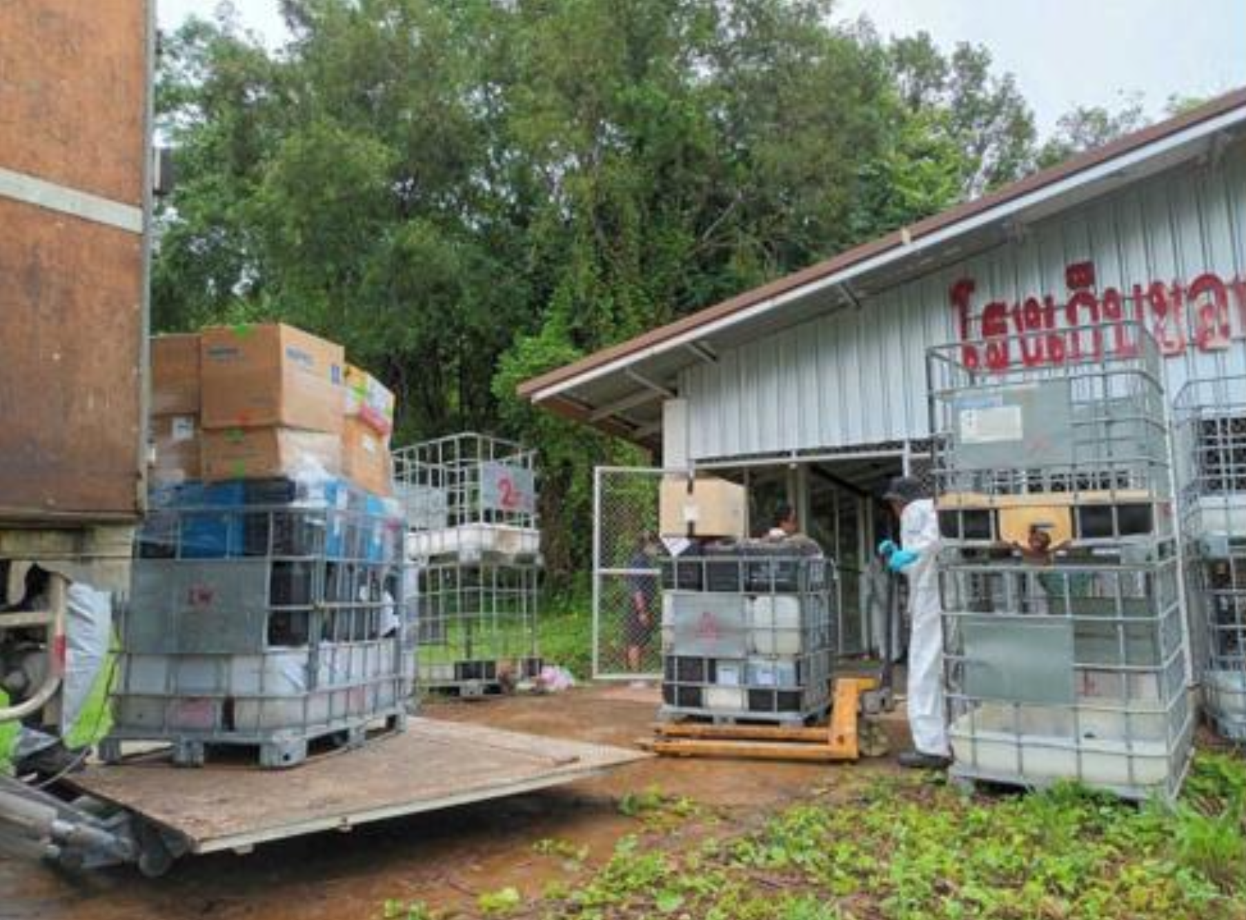 Staff in protective suits managing chemical and hazardous waste containers